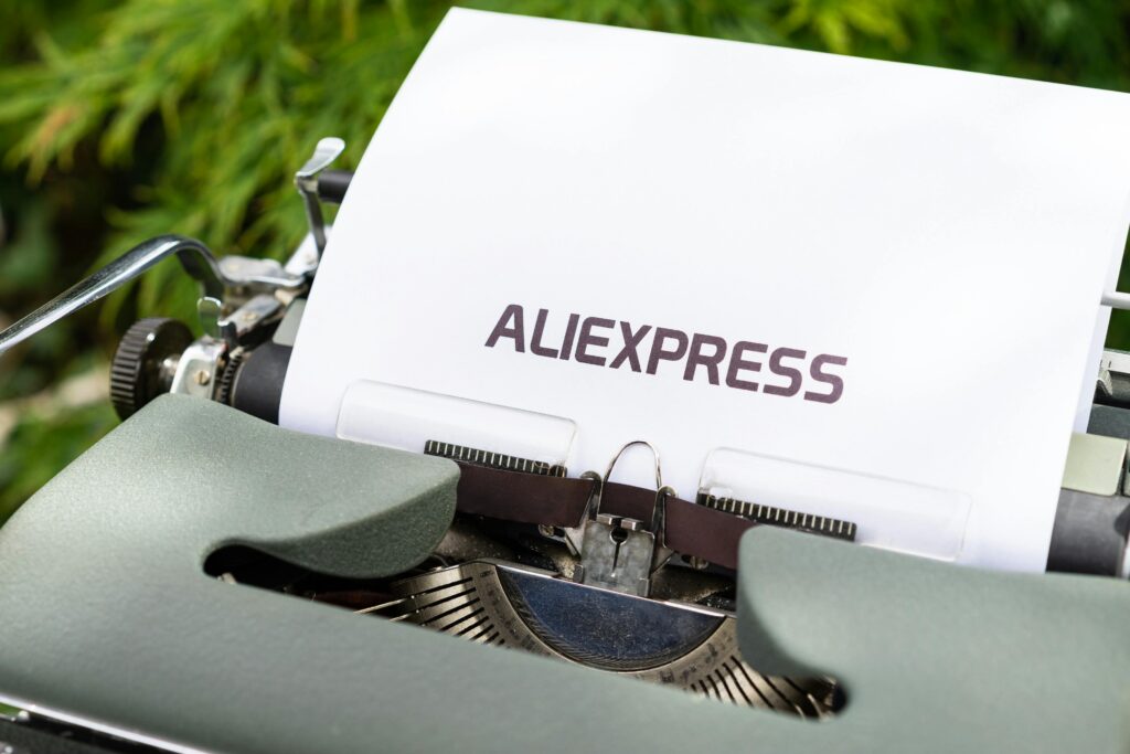 Close-up of a vintage typewriter with Aliexpress text on paper outdoors.